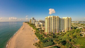 A coastal hotel with multiple high-rise buildings, a sandy beach, and lush greenery. - Ocean View 1 Bedroom Condo (Singer Island)