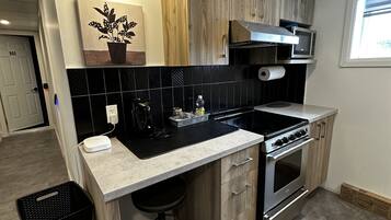 Une cuisine moderne dotée d’un îlot central, de meubles en bois, d’une cuisinière en acier inoxydable et d’un four à micro-ondes.