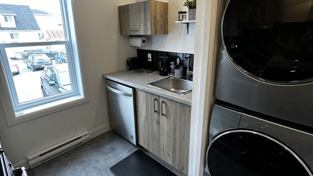 Eine kompakte Küche mit Geschirrspüler, Kaffeemaschine und eingebautem Backofen.