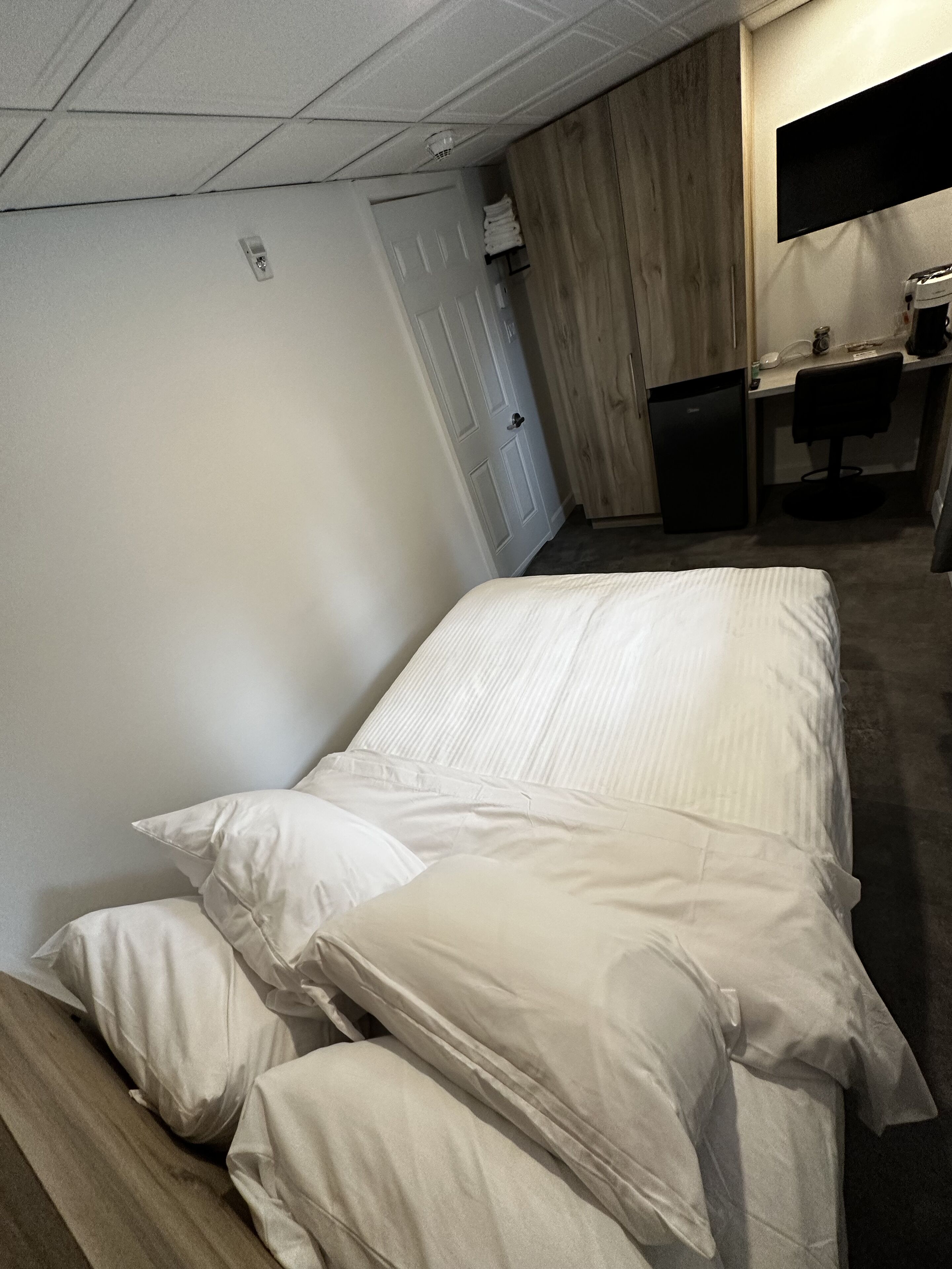 Une chambre d’hôtel avec un lit, un bureau, une chaise et une armoire.