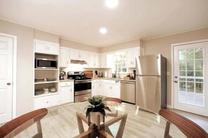 Een moderne keuken met witte kasten, een roestvrijstalen koelkast en een eettafel met stoelen.