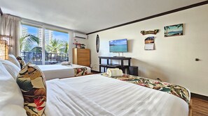 Une chambre d’hôtel avec deux lits, une télévision, un bureau et une vue sur les palmiers et les immeubles.