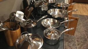 A kitchen with various pots and pans on the stove and countertop.