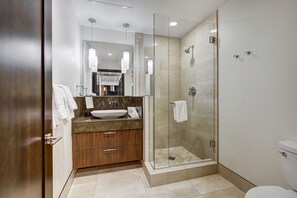 Une salle de bain moderne avec une douche à parois de verre, un meuble-lavabo en bois et un grand miroir.