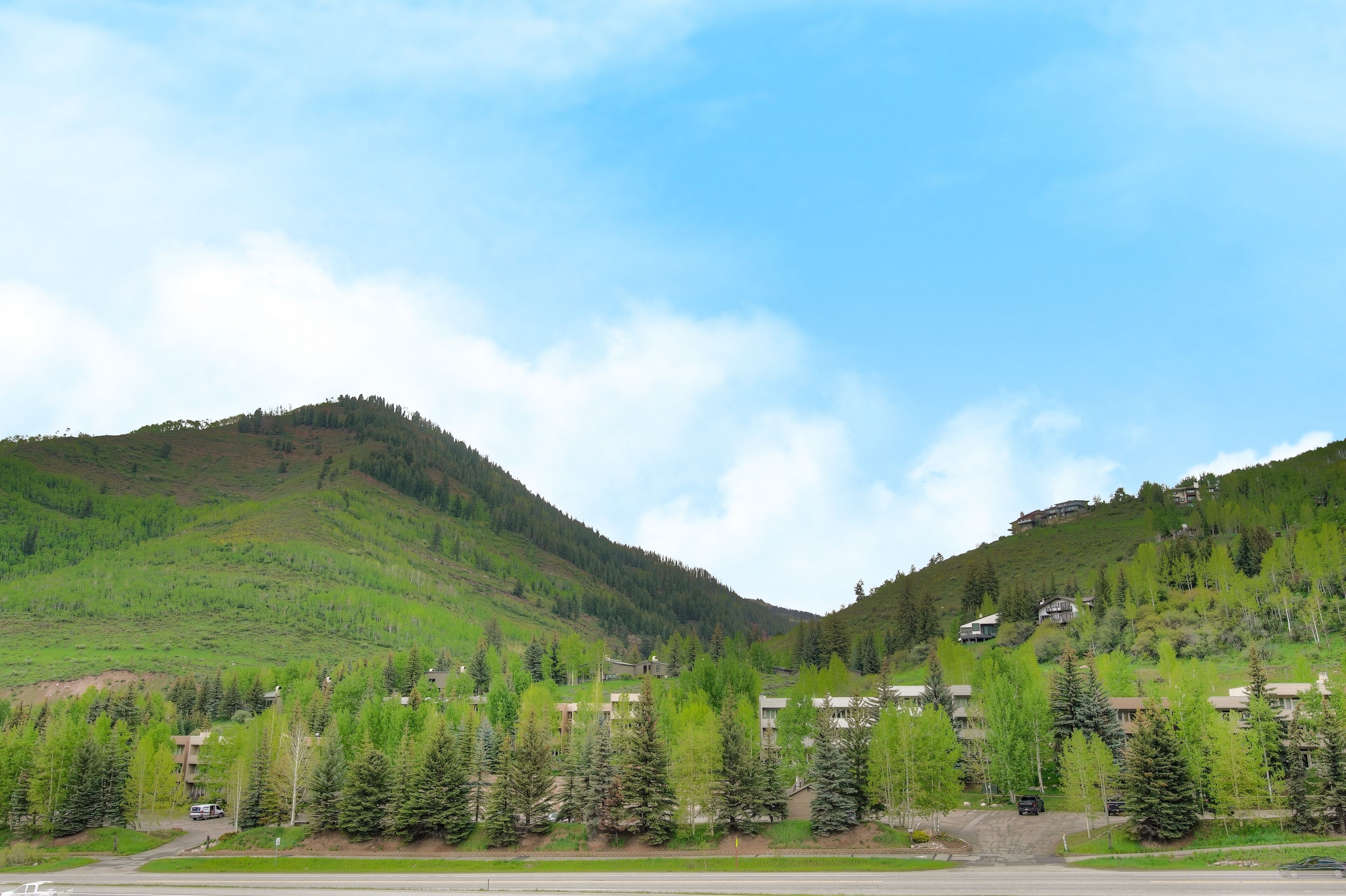 A hotel with multiple buildings on a hillside, surrounded by trees and under a clear sky.