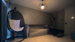 Een moderne woonkamer met een hangstoel, een bank en een bed.
