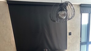 Een eetgedeelte met een tafel en banken, een zwarte achtergrond en een hangende lamp.