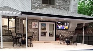 A covered patio with outdoor seating and a television screen. - D'Oasis "Pool Paradise" Hot tub, Sleeps15 Pet friendly, Come Celebrate BOOK IT!  (San Antonio)