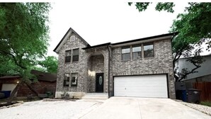 A two-story house with a stone facade, a garage, and a front yard with gravel. - D'Oasis "Pool Paradise" Hot tub, Sleeps15 Pet friendly, Come Celebrate BOOK IT!  (San Antonio)