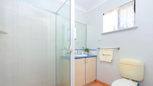 A bathroom with a glass shower enclosure, a sink with a blue countertop, and a toilet with a white tank.