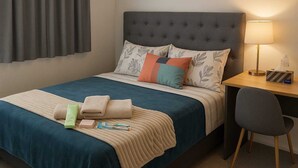 A hotel room with a bed, a desk, and a chair.