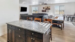 A spacious kitchen with a granite countertop, dark wooden cabinets, and a dining area with a bench and chairs. - Beautiful home at Bear Lake sleeps 20+ with access to Ideal Beach included (Garden City)