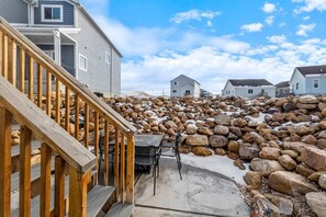 A residential area with a wooden staircase leading to a deck, surrounded by large rocks and snow patches. - Beautiful home at Bear Lake sleeps 20+ with access to Ideal Beach included (Garden City)