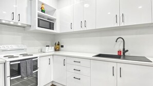 Een moderne keuken met witte kastjes, een roestvrijstalen spoelbak en een ingebouwde oven.