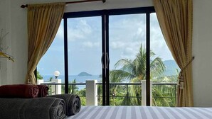A room with a bed, curtains, and a view of palm trees and mountains. - Penthouse Seaview Apartment - 3 Bedroom, Sleeps up to 8 (Tambon Ko Tao)