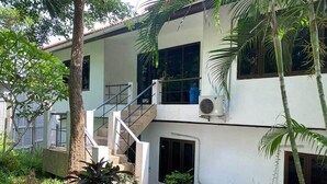 A two-story building with a staircase leading to the upper floor, surrounded by greenery and palm trees. - Penthouse Seaview Apartment - 3 Bedroom, Sleeps up to 8 (Tambon Ko Tao)