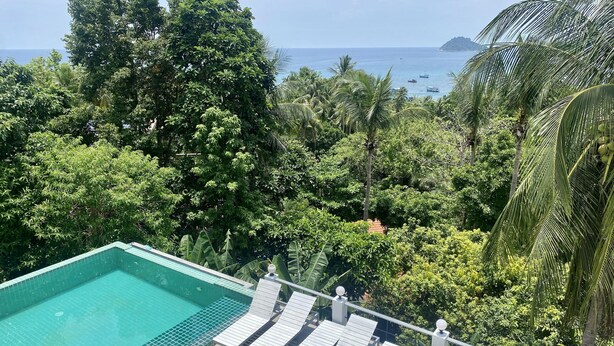 A swimming pool with lounge chairs and a view of the ocean and tropical vegetation. - Penthouse Seaview Apartment - 3 Bedroom, Sleeps up to 8 (Tambon Ko Tao)