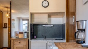 Une cuisine compacte équipée d’une horloge, d’un four à micro-ondes, d’une machine à café et d’un meuble en bois.