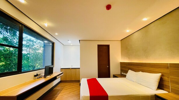 A modern hotel room with a large window, a bed with a red accent, a wooden headboard, and a built-in TV. - SPOT ON 1188 Motel Hoa Cam (Da Nang)