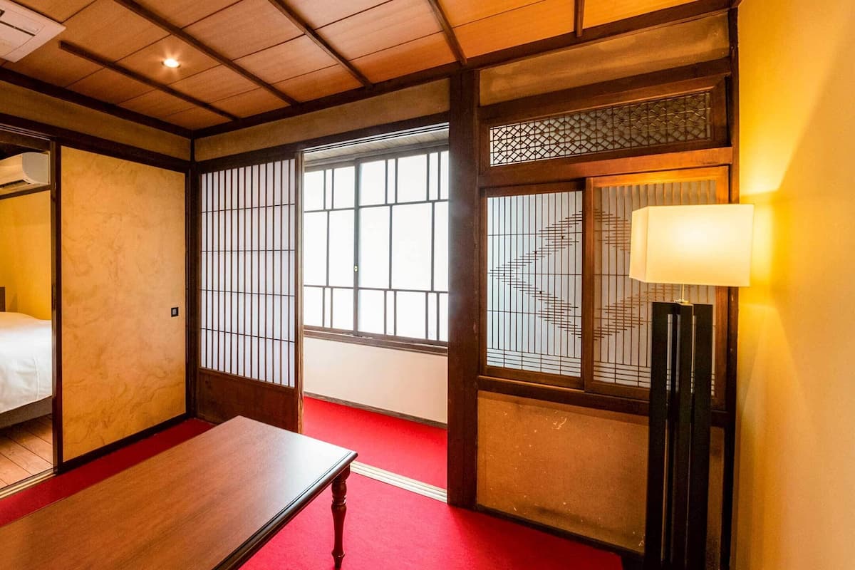 A traditional Japanese-style room with two beds, a wooden table, and sliding doors.