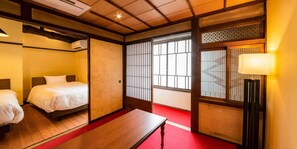 Une pièce de style japonais traditionnel, avec deux lits, une table en bois et des portes coulissantes.