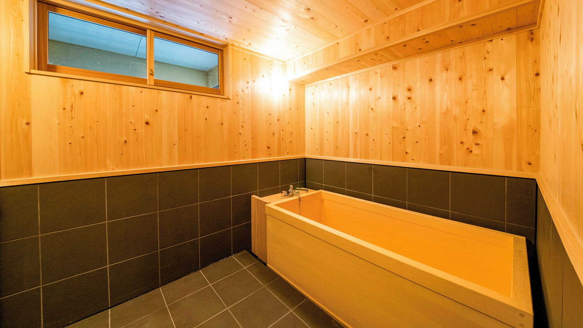 A wooden interior with a bathtub, tiled walls, and a window.