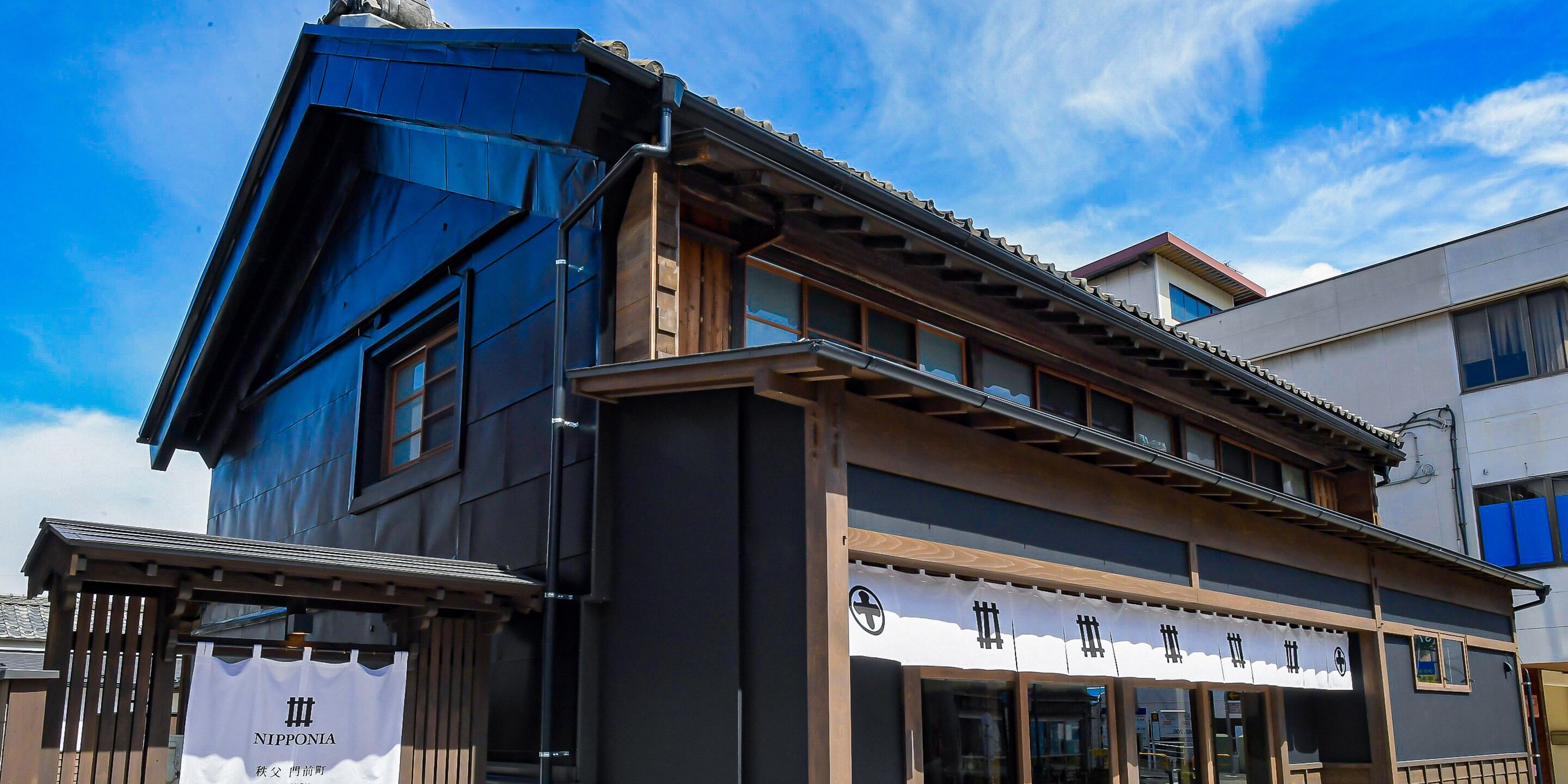 A traditional Japanese building with a modern extension, featuring large windows and a wooden facade.