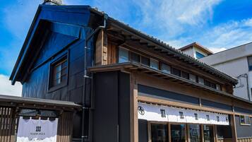 A traditional Japanese building with a modern extension, featuring large windows and a wooden facade.
