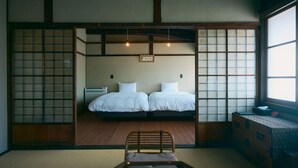 A traditional Japanese-style room with tatami flooring, two beds, a wooden chair, and shoji screens. - NIPPONIA Chichibu Monzenmachi (Chichibu)