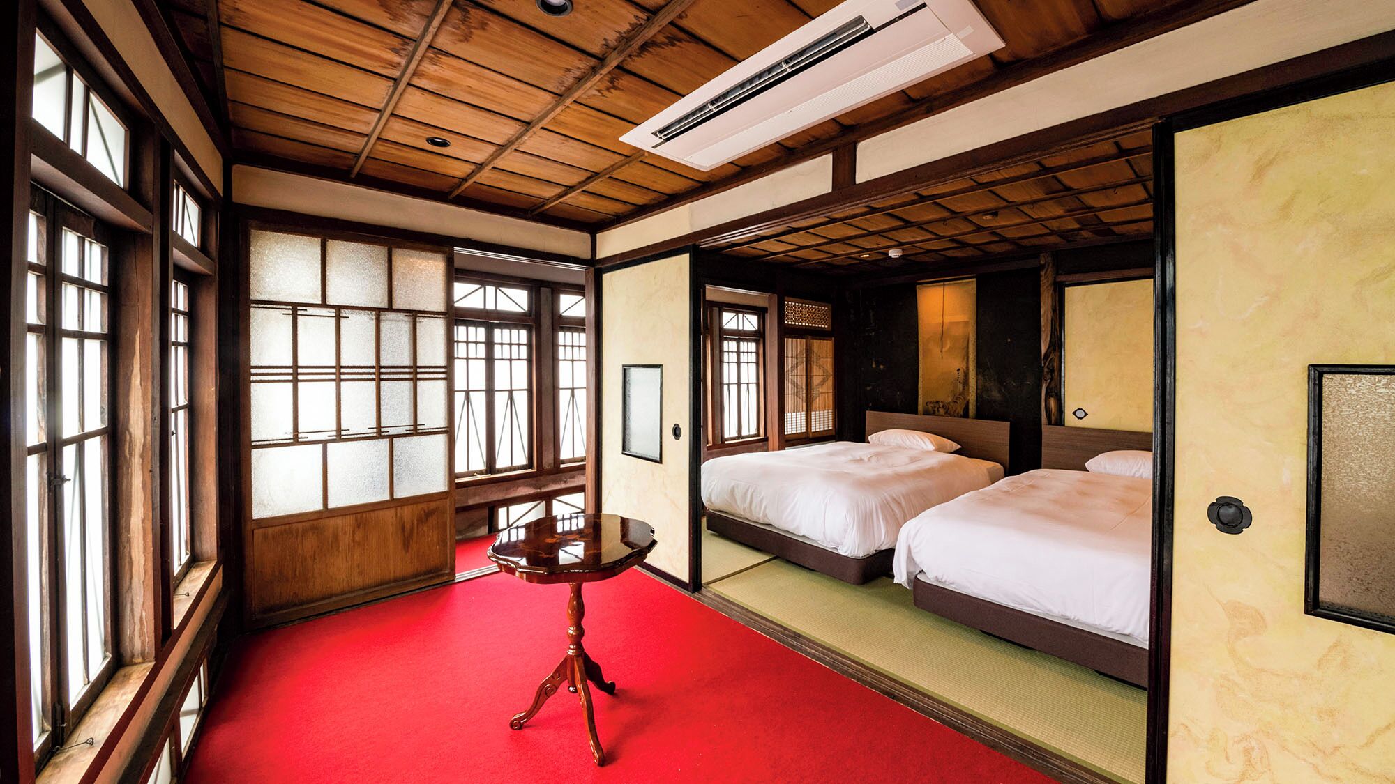 A traditional Japanese-style room with tatami flooring, a wooden ceiling, and sliding doors.