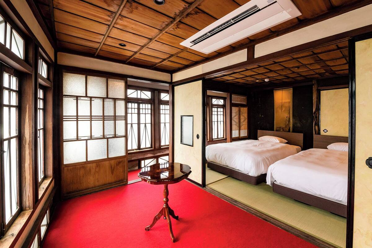 A traditional Japanese-style room with tatami flooring, a wooden ceiling, and sliding doors.