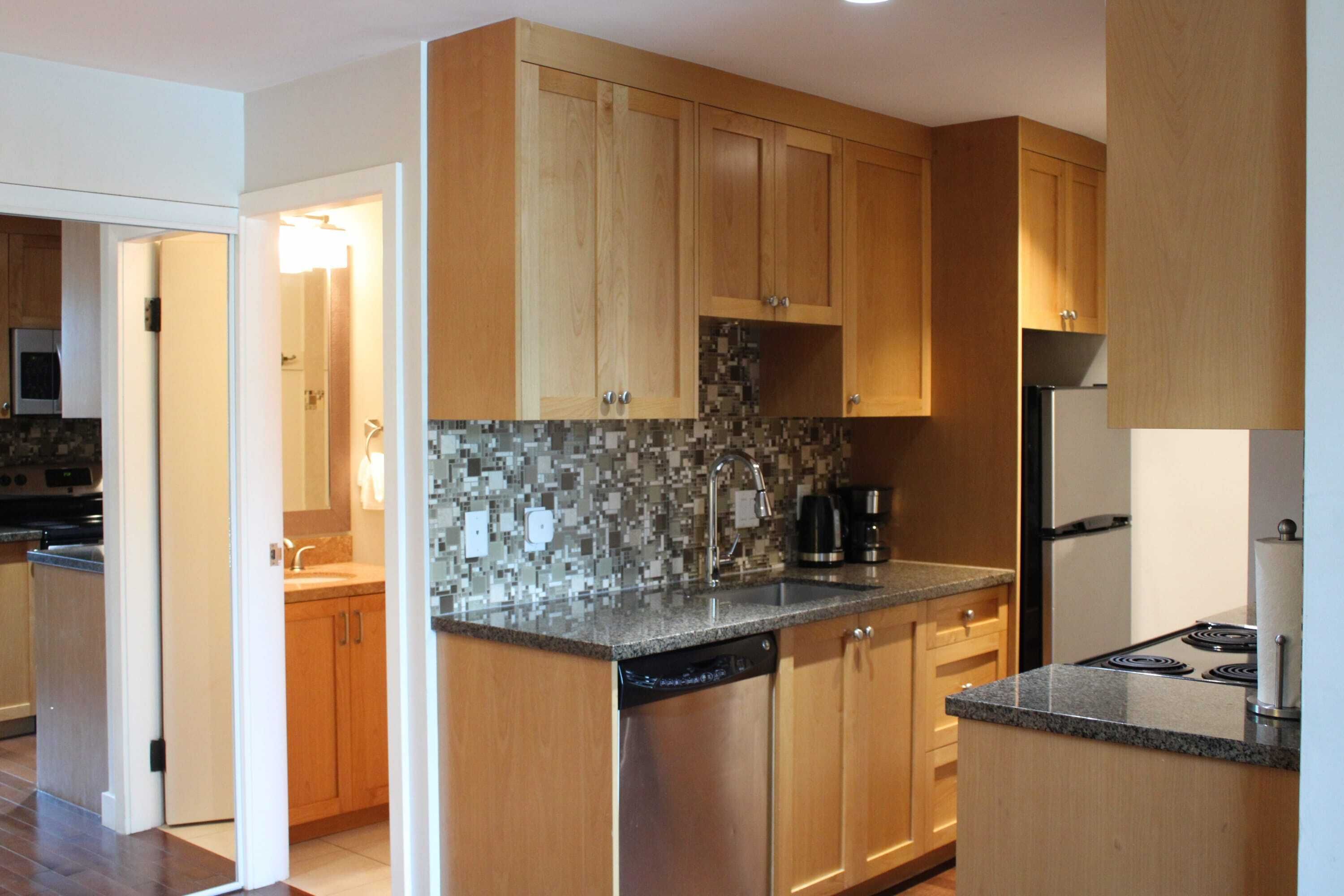 A modern kitchen with wooden cabinets, a tiled backsplash, and a dishwasher.