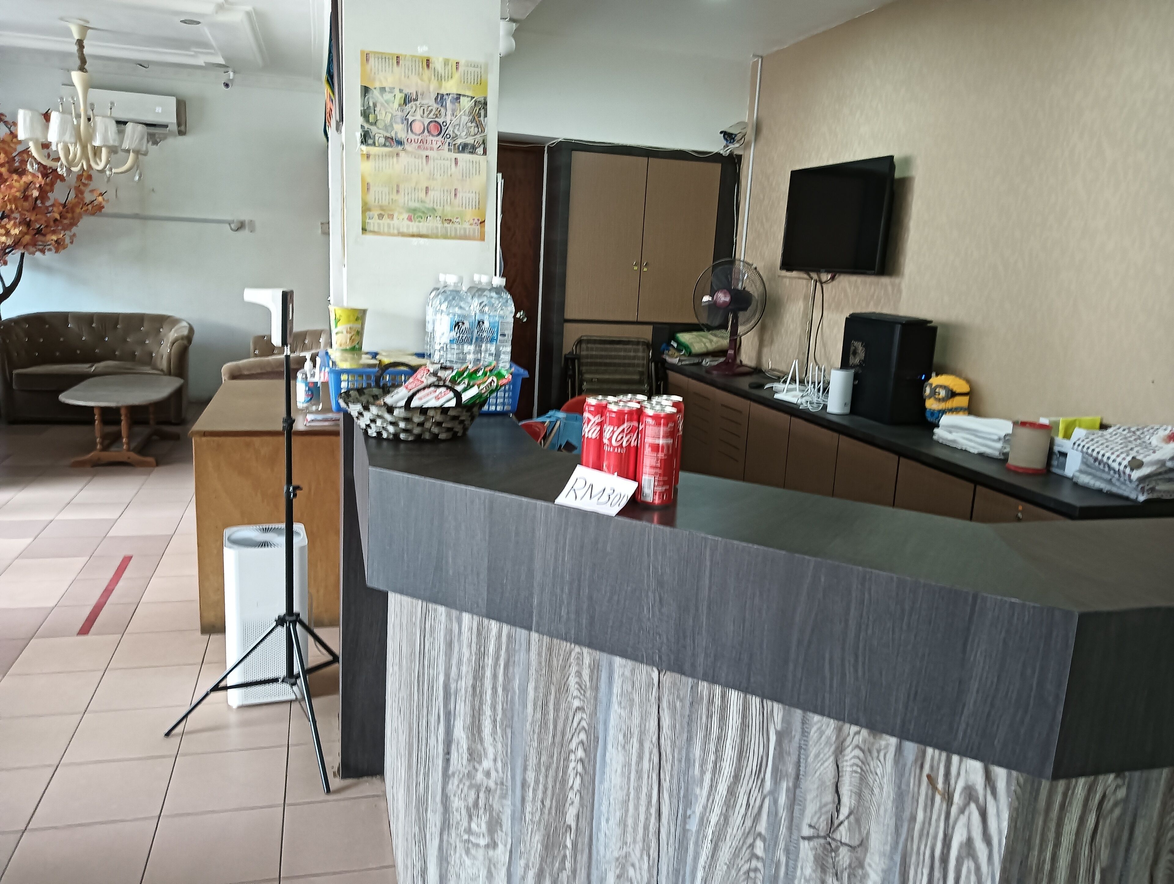 A reception area with a counter, a sofa, a fan, and a television.