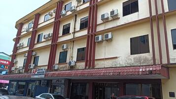 A multi-story building with air conditioning units on the exterior, a red vehicle parked in front, and a storefront with a sign for 'AP Rental & Services'.