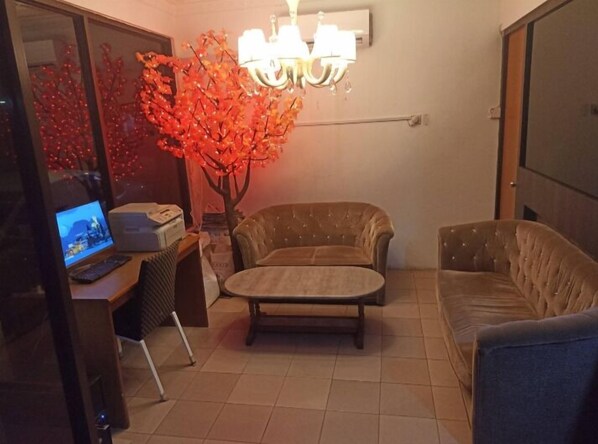 A living room with a sofa, a small table, a TV, and a decorative tree. - Hotel O Oriental Hotel (Sarikei)