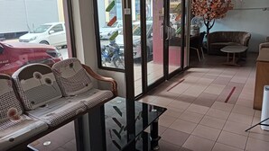 Un vestíbulo de hotel con zona de estar, un separador de vidrio y vistas a coches aparcados fuera.