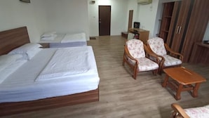 Habitación de hotel con dos camas, un escritorio, dos sillas, un armario y un televisor.