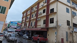 Un edificio de varios pisos con varios establecimientos comerciales en la planta baja, incluyendo una tienda de servicios digitales y un taller de reparación de automóviles.