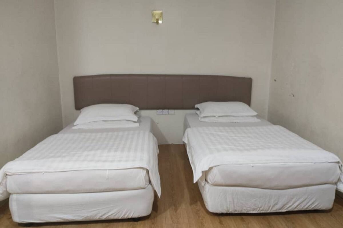 A room with two single beds, each with a headboard and pillows.