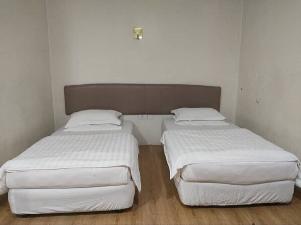 A room with two single beds, each with a headboard and pillows.