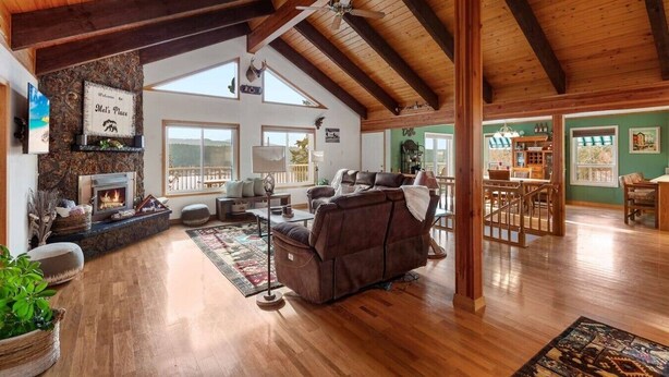 A spacious living room with a fireplace, wooden beams, a sofa, and a bar area. - Lakeview Mel's Place (Bayview)