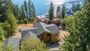 A cabin with a sloped roof, surrounded by dense forest and a lake. - Lakeview Mel's Place (Bayview)