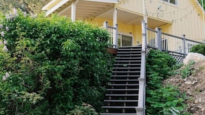 A yellow house with a porch, a staircase leading to the entrance, and a number '106' on the wall. - Hilltop Retreat w/ Lake & Mountain Views (Hope)