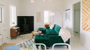 A living room with a green sofa, a fireplace, a wooden sideboard, and a patterned rug. - Hilltop Retreat w/ Lake & Mountain Views (Hope)