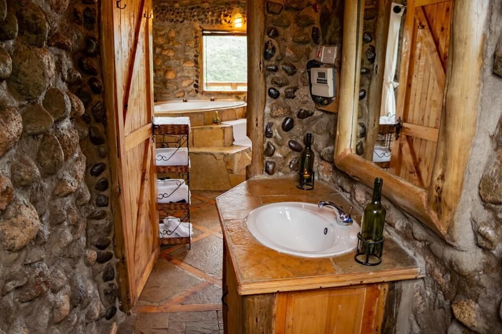 Un baño rústico con pared de piedra, tocador de madera y un espejo grande.