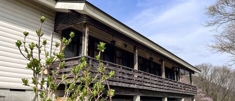 A building with a porch supported by wooden beams, large windows, and a covered area with a roof.