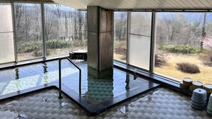 An indoor swimming pool with clear glass walls, a tiled floor, and a view of a forested area. - Kiyokawa High-land Recreation Center (Aga)