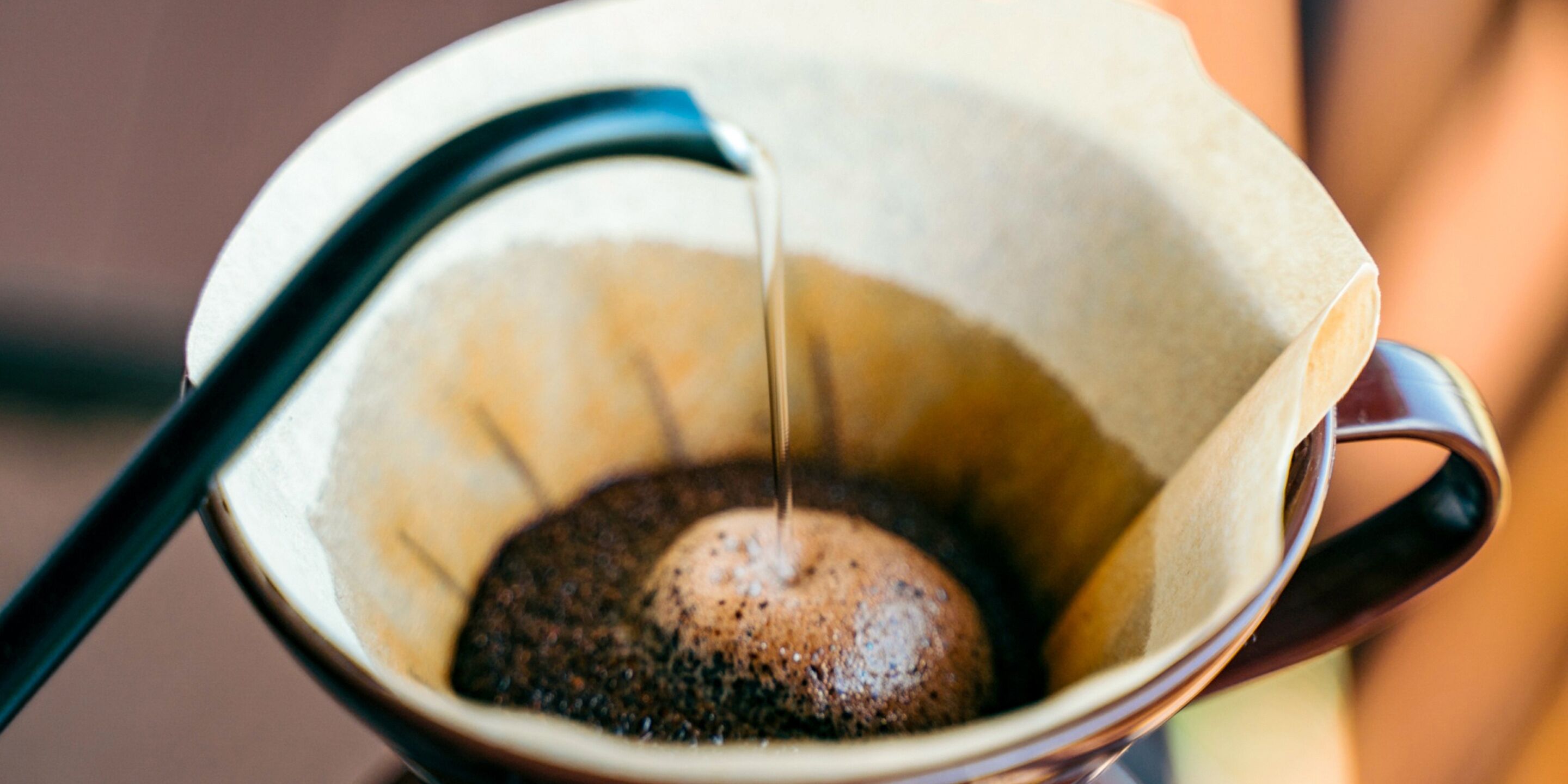 Eine Kaffeemaschine mit einem dunkel gerösteten Kaffeebohnen und klarer Flüssigkeit, die in eine Tasse tropft.