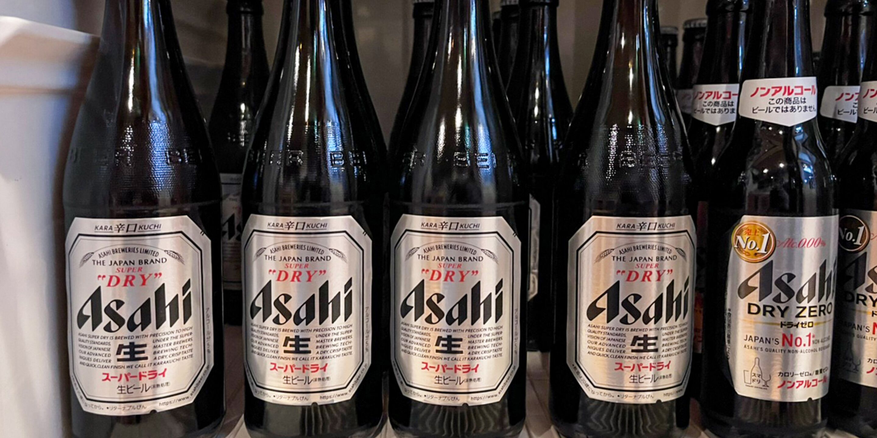 A row of Asahi beer bottles with labels.