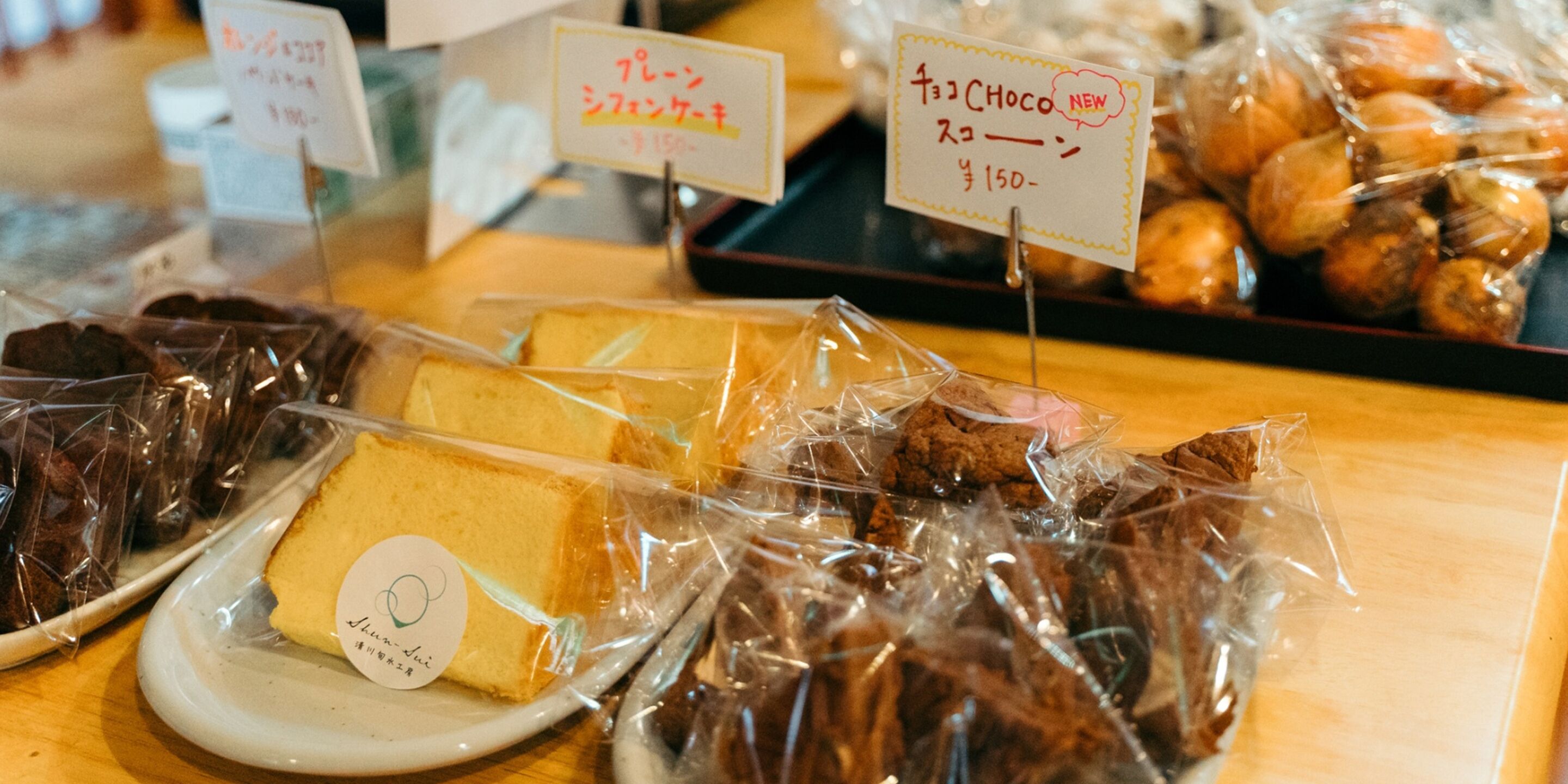 A variety of packaged desserts on display, including cakes and pastries, with price tags visible.